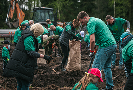 Adults and children planting trees in a field in Poland.